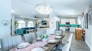 A modern dining area with a long table set for six, surrounded by grey upholstered chairs. - Luxury & Spacious/Large pool/BBQ/Game room/Pool (Miami)