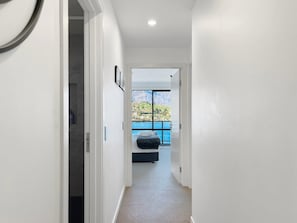 A narrow hallway leading to a balcony with a view of a mountainous landscape.
