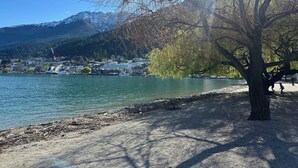 Une vue sur le lac, avec un arbre, un quai et des bâtiments en arrière-plan.