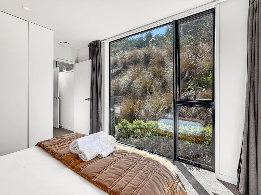 Bright bedroom with floor-to-ceiling windows looking onto the surrounding hillside