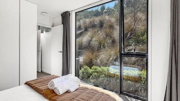 Bright bedroom with floor-to-ceiling windows looking onto the surrounding hillside