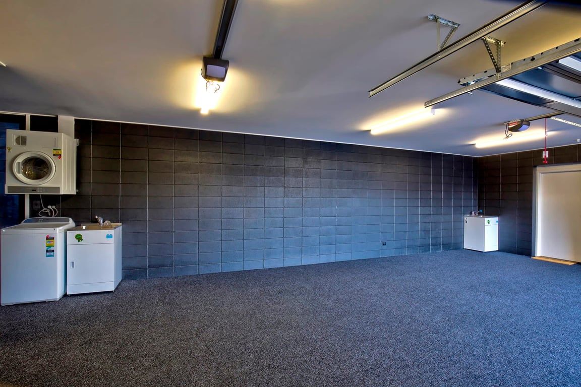 A laundry room with a washing machine, dryer, and a tiled wall.