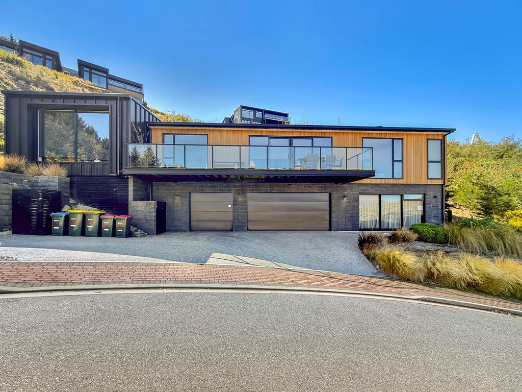 A modern two-story house with a garage, large windows, and a sloped roof.