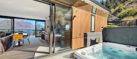 Un espacio exterior moderno con un jacuzzi, una mesa de comedor y un sofá.