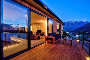 Un intérieur moderne avec une grande porte vitrée, un plancher en bois et un coin salon comprenant un canapé et une table.