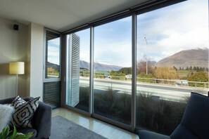 A modern living room with large windows, a sofa, and a lamp.