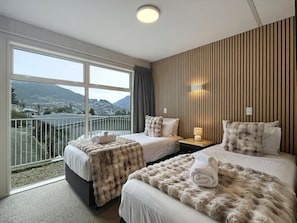 Una camera d'albergo con due letti, un balcone vista e un pannello a parete in legno.