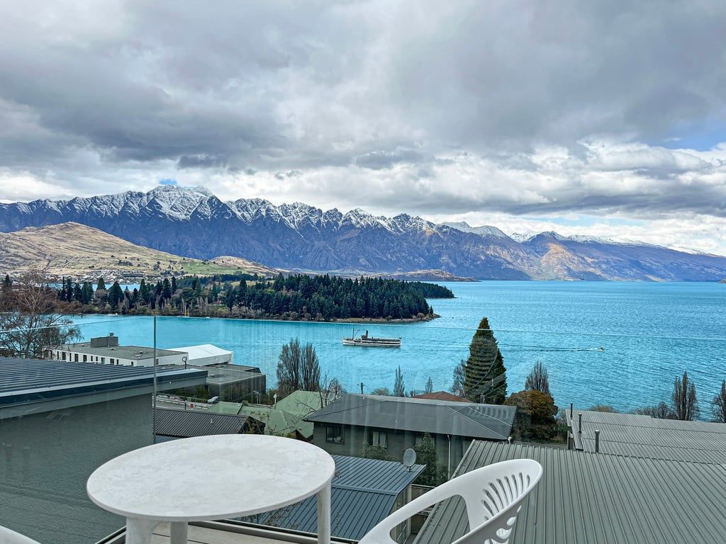 A terrace with a table and chairs overlooking a lake with mountains in the background.