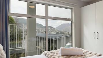Ein Schlafzimmer mit großem Fenster, einem Bett mit weißer Decke und einem Kleiderschrank.