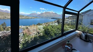 Ett rum med ett stort fönster som erbjuder utsikt över en sjö, berg och ett bostadsområde.