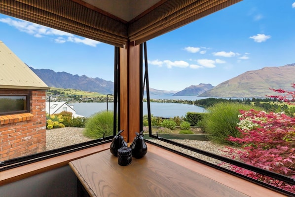 A room with a large window overlooking a lake and mountains.