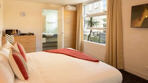 A hotel room with a bed, a bedside table, a mirror, a window with curtains, and a view of the outside. - Marina 303A-Studio (Queenstown)