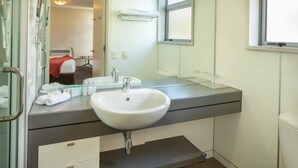 A modern bathroom with a white sink, a mirror, and a window. - Marina 303A-Studio (Queenstown)