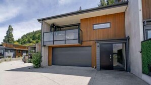 A modern two-story house with a garage, a balcony, and a driveway. - Remarkable Lake View (Queenstown)