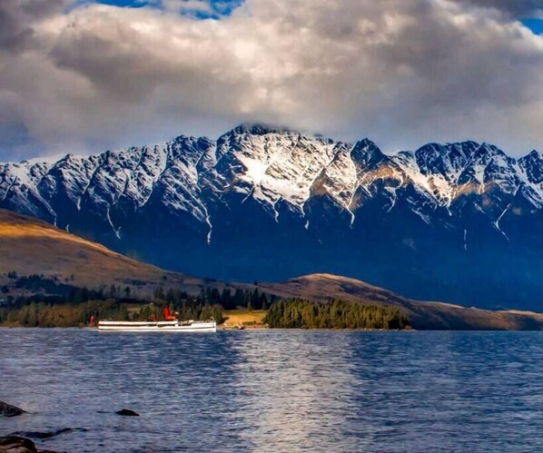 Un lac avec un bateau et, en arrière-plan, des montagnes enneigées.
