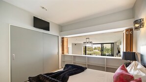 Een moderne slaapkamer met een groot bed, een tv aan de muur en uitzicht op een berglandschap door het raam.