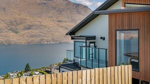 A modern house with a wooden facade, large windows, and a view of a lake and mountains. - Lakeview Paradise On Wynyard (Queenstown)