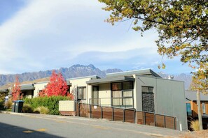 Un edificio moderno con techo plano, grandes ventanales y vistas a montañas al fondo.