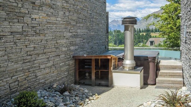 A stone wall, outdoor seating, a hot tub, and a poolside area with a mountain view. - Budget 1 Bedroom Studio Pounamu 224B Garden View (Queenstown)