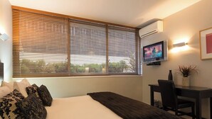 A bedroom with a bed, a desk, and a television. - Budget 1 Bedroom Studio Pounamu 224B Garden View (Queenstown)