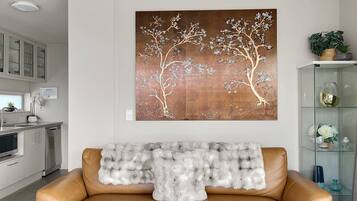 A modern living room with a sofa, a decorative wall piece, and a glass cabinet with items.