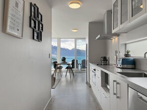 A modern kitchen with a view of mountains and a dining area with chairs and a table.