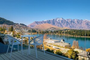 A deck with white chairs overlooking a lake and mountains.