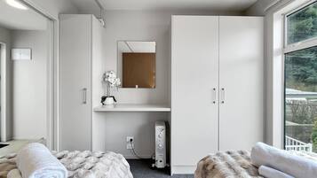 A modern bedroom with a large wardrobe, a mirror, and a view of the outdoors.