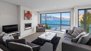 A modern living room with a large window offering a mountain view, a flat-screen TV, and a fireplace.