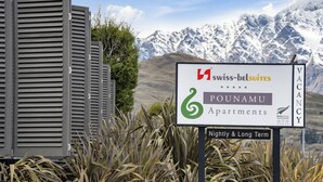 A sign for Swiss-belSuites Pounamu Apartments advertising nightly and long-term vacancies.