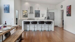 Een moderne keuken met een centraal eiland, barstoelen en een eettafel voor vier personen.