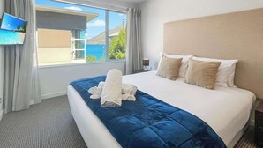 Une chambre d’hôtel avec un grand lit, un téléviseur fixé au mur et une vue sur la mer.