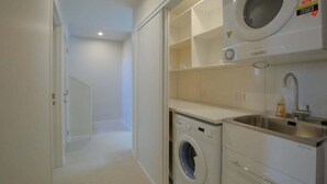 A compact kitchen with a washing machine, a sink, and a small countertop.