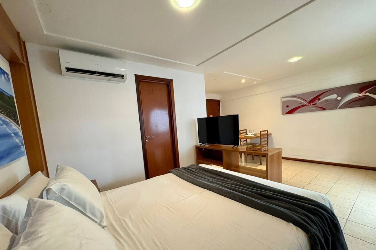 Una habitación de hotel con cama, televisión, escritorio y un cuadro en la pared.