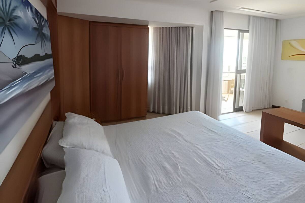 Una habitación de hotel con una cama grande, un armario de madera, un cuadro y vistas al exterior.