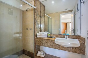 Un baño con cabina de ducha de vidrio, un lavabo con encimera de mármol y un espejo que refleja la habitación.