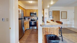 A kitchen with wooden cabinets, stainless steel appliances, and a wooden island with a trash can. - Close to Lifts | Large Balcony | Mountain Spirits 103 (Angel Fire)