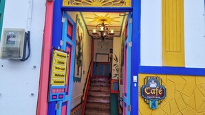 A colorful hostel entrance with a sign reading "Mythos hostel" and a staircase leading inside. - Hostal Mythos (Filandia)