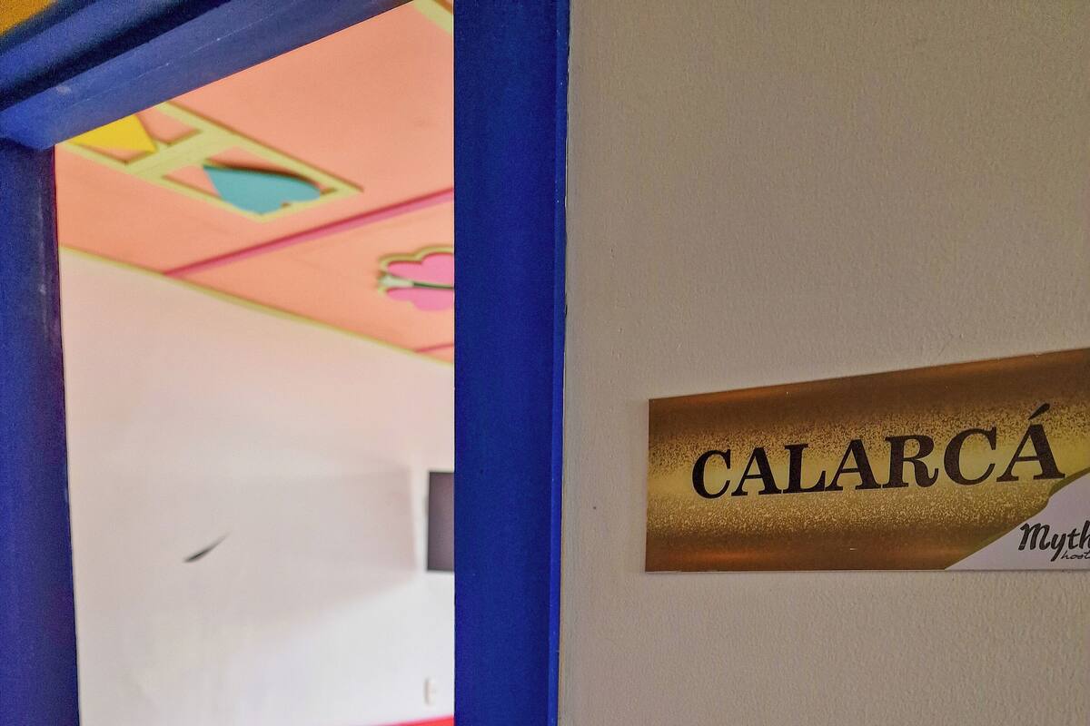 Una habitación con una cama, un letrero que dice "CALARCÁ" y un marco de puerta.