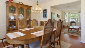 A dining room with a wooden table, chairs, a chandelier, and a cabinet with glass doors. - World Cup Work Base -Large Home + OFFICE- Sleeps 8 (Stonecrest)