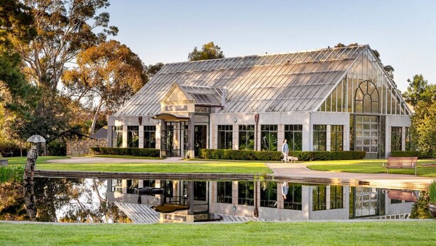 Un grand bâtiment de style serre, avec un bassin aux reflets argentés situé devant.