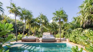 A pool with lounge chairs and a stone wall, surrounded by tropical plants. - ANANA Casa Kaab Kaan (Tulum)