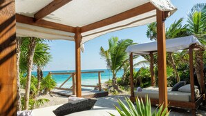 A beachside cabana with a wooden frame, a cushioned seating area, and a view of the ocean. - ANANA Casa Kaab Kaan (Tulum)