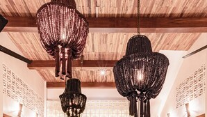 A spacious dining area with a large round table surrounded by chairs, a kitchen area with wooden cabinets, and a hanging chandelier. - ANANA Casa Kaab Kaan (Tulum)