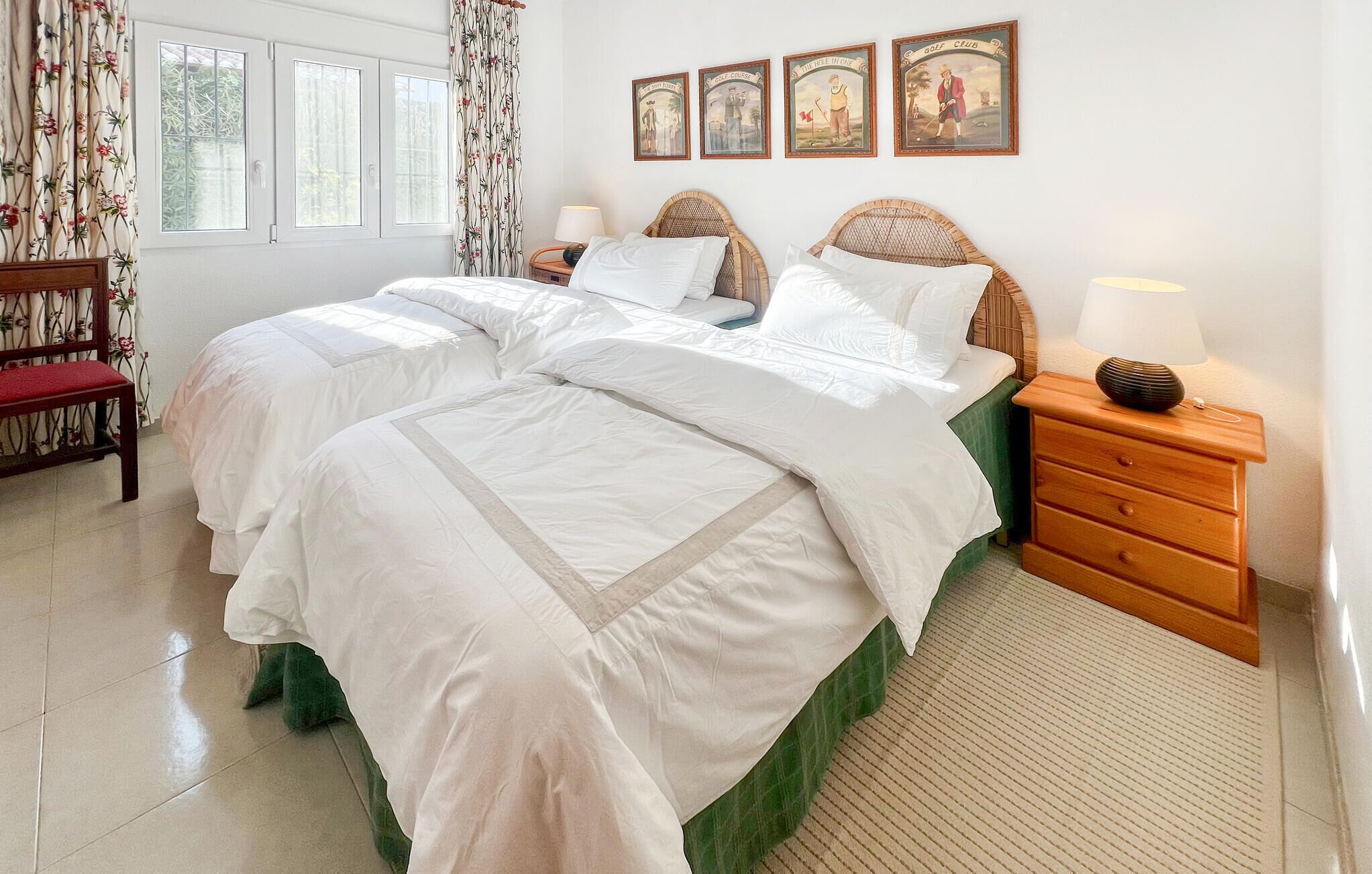 A double bed with white bedding, a wooden nightstand with a lamp, and a green chair.