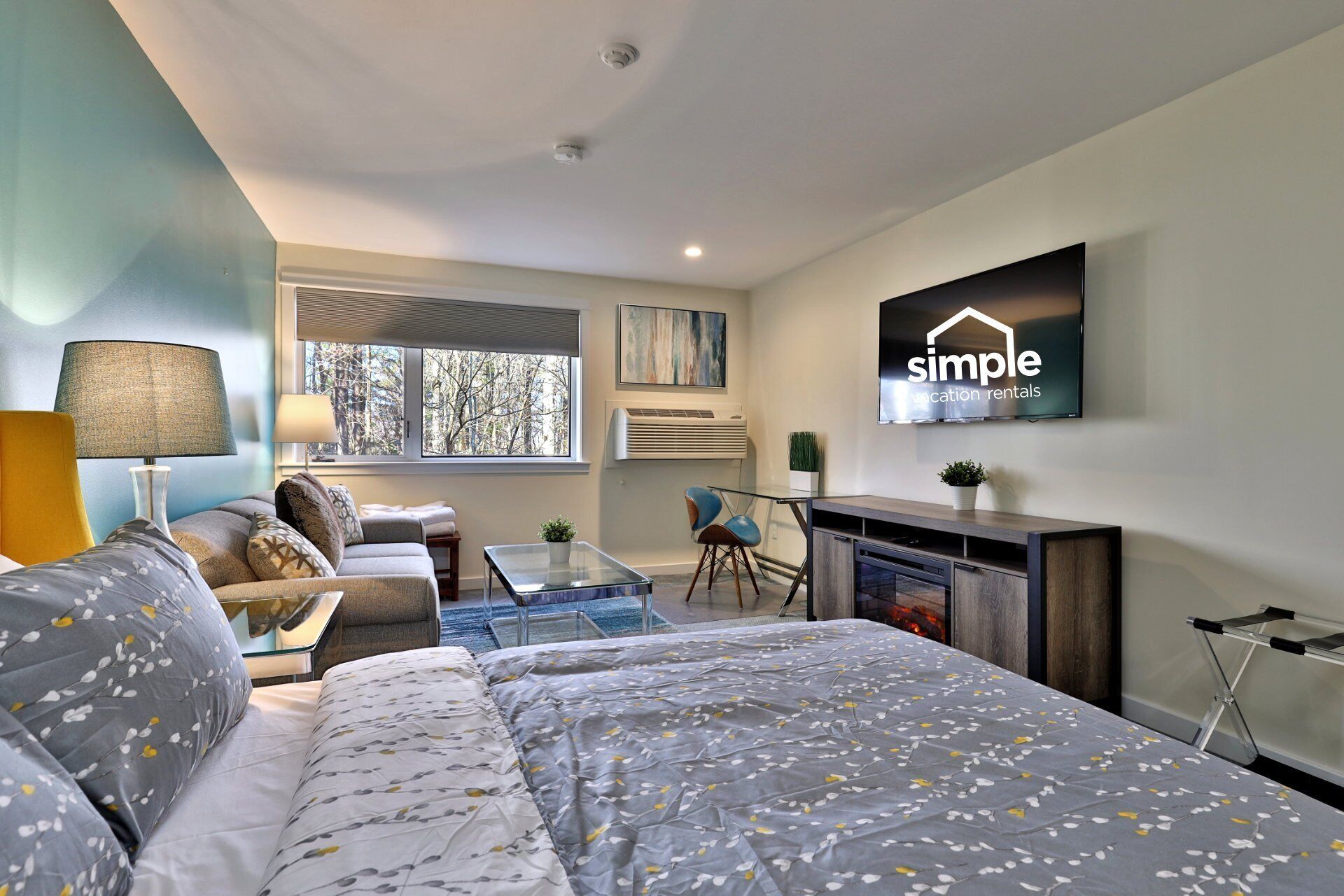 Une chambre d’hôtel moderne équipée d’un lit, d’un canapé et d’un téléviseur diffusant des annonces de « locations de vacances simples ».