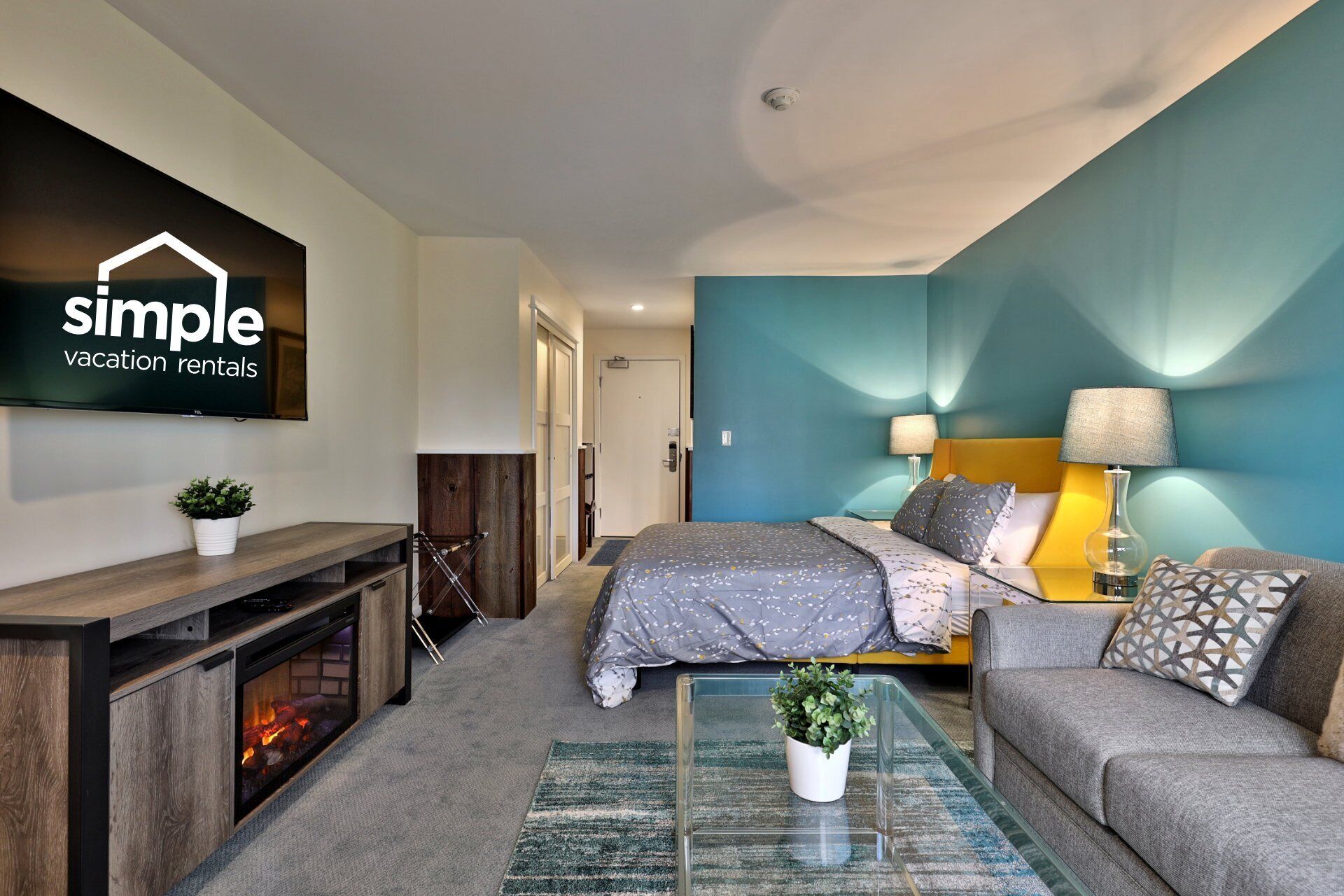 A modern bedroom with a bed, sofa, and a fireplace.
