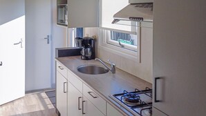 Uma cozinha moderna com uma pia de aço inoxidável, uma cafeteira e um fogão a gás.