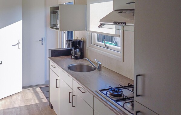 A modern kitchen with a stainless steel sink, a coffee maker, and a gas stove.