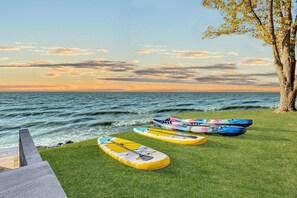 Una zona erbosa con diversi paddleboard e kayak vicino al mare al tramonto.